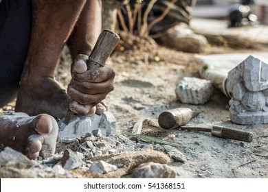 Man Barefoot Sculpting A Rock With A Chisel At Chamundi Hills In Mysore, India. Indian Sculptor Working On Street