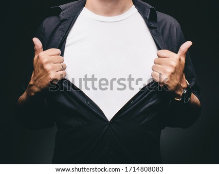 Man baring chest doing superman superhero pose revealing blank t-shirt with copy space