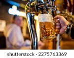 man bartender hand at beer tap pouring a draught beer in glass serving in a restaurant or pub