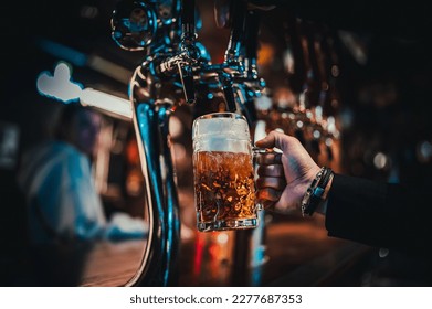 man bartender hand at beer tap pouring beer in glass in bar or pub - Powered by Shutterstock