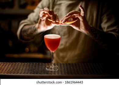 Man Bartender Holds Lemon Peel In His Hands And Sprinkles On Glass With Bright Cocktail.