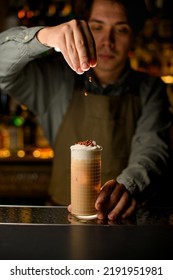 Man Bartender Neatly Pour Chocolate Balls On Glass With Grid Pattern Full Of Cocktail With Whipped Cream