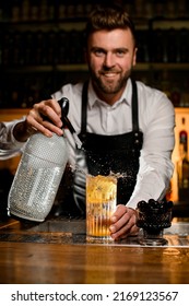 Man Bartender Skilfully Adds Carbonated Liquid From Siphon To Transparent Glass With Cold Freshness Cocktail On Bar Counter