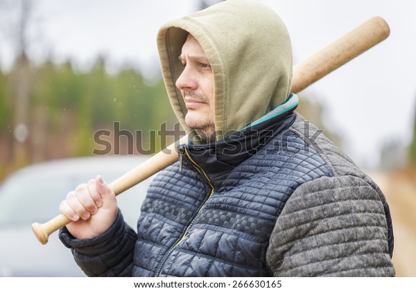 Man with a baseball bat near\
car