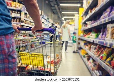 Man with a basket walks in a supermarket. Hand and part of the basket in focus, blurred background - Shutterstock ID 2205878131