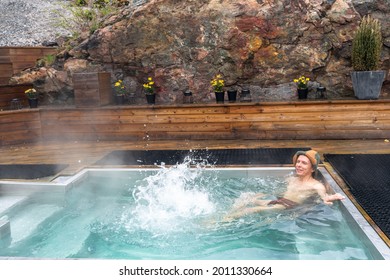 Man Bathes Or Takes Bath In Small Pool With Hot Water. Hot Springs For Bathing And Wellness Are Specially Equipped. Healthy Mid Aged Male Relaxing With Outdoor Spa Treatments. SPA Hotel Lifestyle.