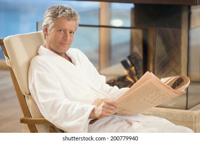 Man In A Bathrobe Sitting In Deckchair Holding Newspaper Smiling