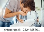 Man in bathroom, brushing teeth and rinse with water, morning cleaning routine for health and wellness in home. Dental care, mouthwash and toothbrush, male grooming for fresh breath and oral hygiene.