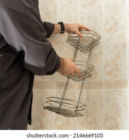 A Man In The Bathroom Is Dismantling An Old Chrome Bunk Shelf Covered With Rust And Fungus. Copy Space.