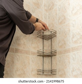 A Man In The Bathroom Unscrews The Screws With A Screwdriver Dismantling An Old Chrome Bunk Shelf Covered With Rust And Fungus