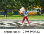 Man battles with an umbrella bending inward under the force of strong winds, man caught in downpour. Person navigating crosswalk in the rain suffers from strong wind. Motion blur effect, soft effect