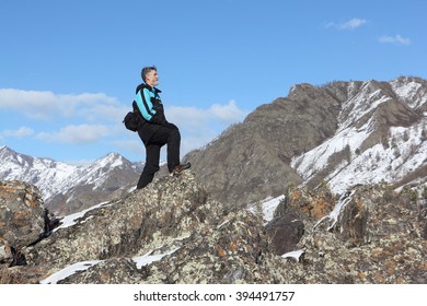 The man with a beard in a black jacket going by the rock in the mountain district, Altai, Russia