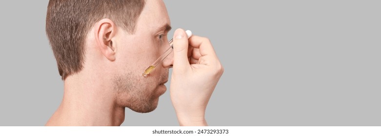 Man beard care routine. Oil pipette near male face. Hair serum product. Haircare facial treatment. Applying healthy cosmetics. Beauty skincare hydration. Horizontal banner with copyspace - Powered by Shutterstock