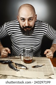 Man With A Beard Drinking Beer And Eating A Fish