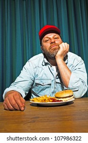 Man With Beard Eating Fast Food Meal. Enjoying French Fries And A Hamburger. Trucker With Red Cap.