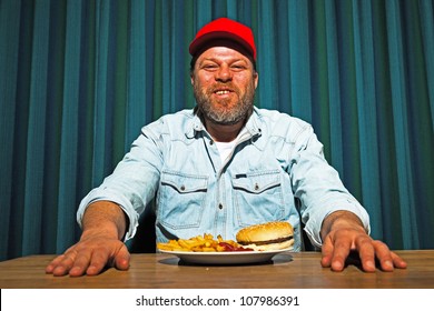 Man With Beard Eating Fast Food Meal. Enjoying French Fries And A Hamburger. Trucker With Red Cap.