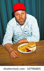 Man With Beard Eating Fast Food Meal. Enjoying French Fries And A Hamburger. Trucker With Red Cap.