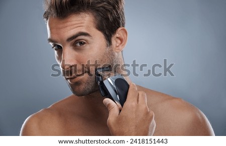 Man, beard and electric razor in studio portrait for grooming, skincare and wellness by grey background. Person, model and shaving with hygiene, facial hair removal and product for cosmetic change