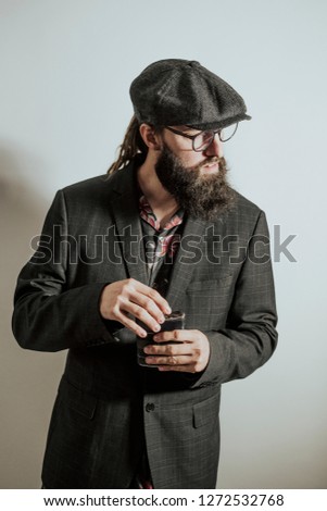 Man with beard, glasses and hat that drinks alcohol
