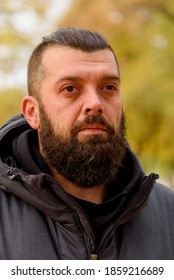 Man with a beard in a gray jacket on the street. Portrait of a man. The guy with the beard.