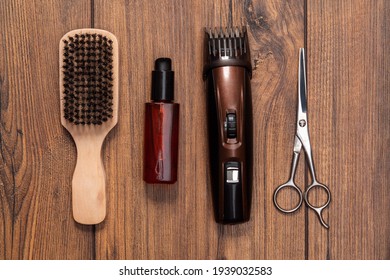 Man beard grooming items on a wooden table surface, wooden comb, scissors, oil and electric trimmer