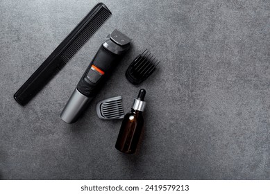 Man beard grooming items on a stone table surface, comb, oil and electric trimmer - Powered by Shutterstock