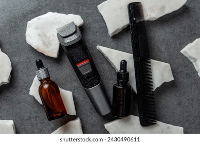 Man beard grooming items on a stone table surface, comb, oil and electric trimmer - Powered by Shutterstock