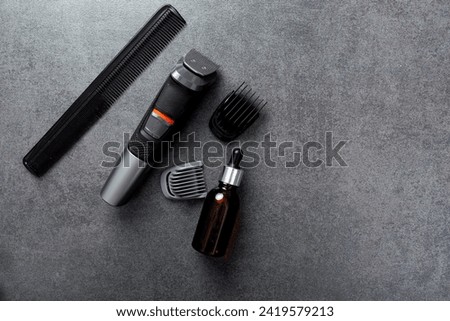 Man beard grooming items on a stone table surface, comb, oil and electric trimmer