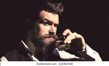 Man With Beard Holds Glass Brandy. Bearded Drink Cognac. Sommelier Tastes Drink. Man Holding A Glass Of Whisky. Sipping Whiskey. Portrait Of Man With Thick Beard. Macho Drinking. Degustation, Tasting.