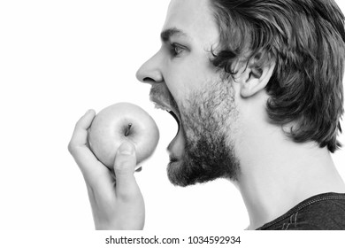 Man with beard and moustache going to bite green apple with his mouth open, side view. Isolated on white background. Healthy nutrition concept