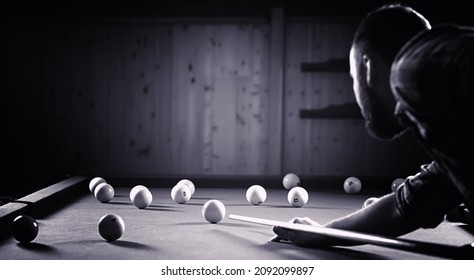 A man with a beard plays a big billiard. Party in 12-foot pool. Billiards in the club game for men. A man with a cue breaks the pyramid. - Shutterstock ID 2092099897