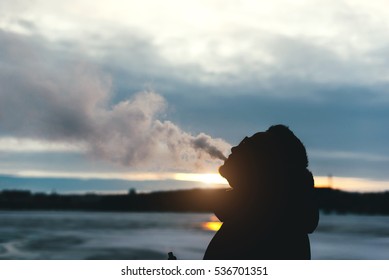 Man with beard smoke electronic cigarette outdoor.