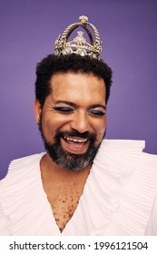 Man With Beard Wearing Makeup And Crown. Portrait Of A Happy Drag Queen Against Purple Background.