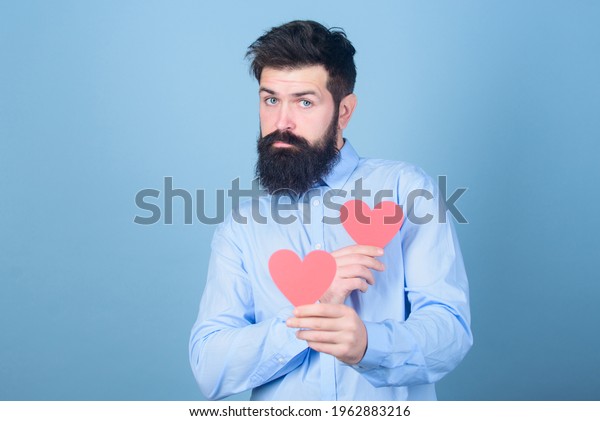 Man bearded hipster with heart valentine card.\
Celebrate love. Guy attractive with beard and mustache in romantic\
mood. Feeling love. Dating and relations concept. Happy in love.\
Falling in love