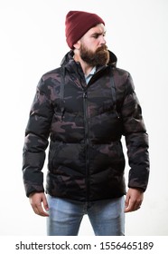 Man Bearded Stand Warm Camouflage Pattern Jacket Parka Isolated On White Background. Hipster Winter Fashion. Guy Wear Hat And Black Winter Jacket. Comfortable Winter Outfit. Winter Stylish Menswear.