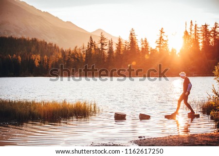 Man and beautiful morning scenery in nature. Lake, mountains, gold rays. Strbske pleso, High Tatras, Slovakia