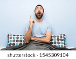 Man in bed pointing up and surprised
