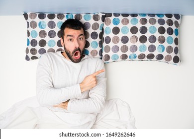 Man In Bed In Top View Surprised And Pointing Side
