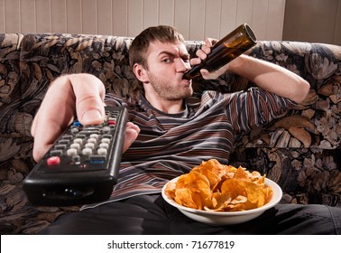 Man with beer and chips watching TV at home