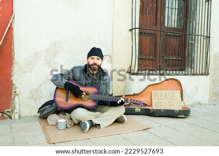 Man beggar living in poverty playing the guitar to sing a song and ask for money on the street