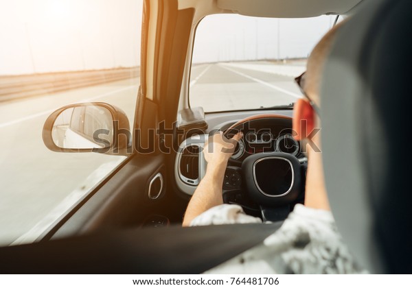 The\
man behind the wheel of a car traveling on the\
road