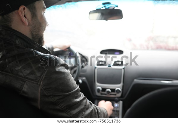 The man behind the wheel of a car while driving in\
rainy day