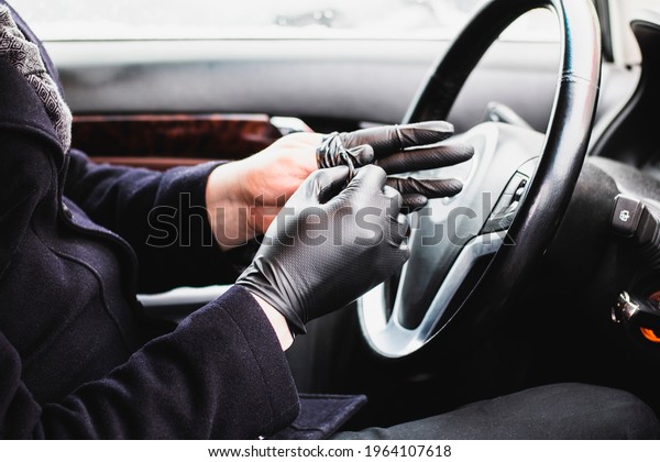 The man behind the wheel removes\
or wears gloves to protect against coronavirus\
infection.