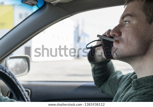  the man behind the wheel talking on\
the phone with a cigarette in his mouth\
grimaced.