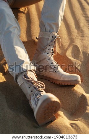 Man in beige clothes and boots sits in the desert. Caucasus, Russia