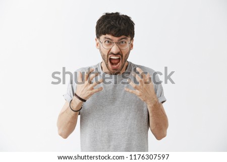 Man being fed up gathering negative emotions inside yelling and shouting expressing anger and outrage being mad and hateful screaming cursing words at camera grimacing and clenching hands over chest