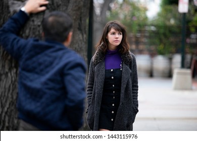 Man Being Rude, Leering And Cat Calling Or Sexually Harassing A Woman Walking On The Street.  Also Depicts Crime And Safety With A Stalker Following A Female Victim.  