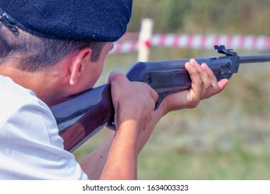 A man in a beret takes aim or shoots with a gun. Back view. Selective focus