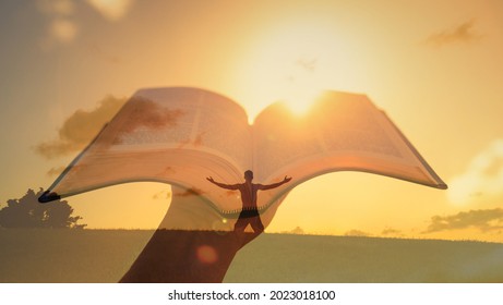 Man With Bible And Open Arms Up To The Sky In Worship Prayer. Christian Religion Spiritual Belief Concept Background. 