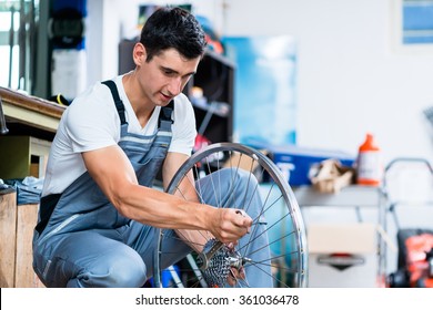 Man As Bicycle Mechanic Working In Workshop